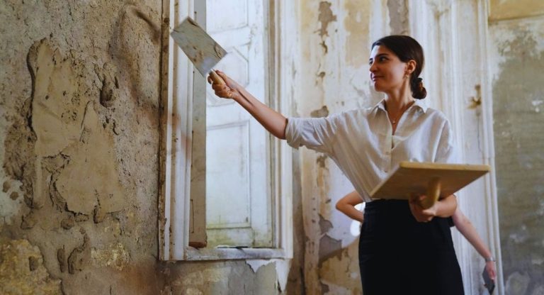 Femme appliquant de l'enduit à la chaux sur un mur intérieur avec une taloche