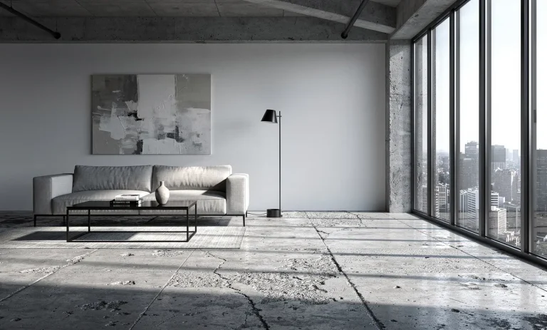Salon moderne à sol en béton brut, baigné de lumière naturelle à travers de grandes fenêtres et à la décoration minimaliste soulignant une ambiance industrielle.
